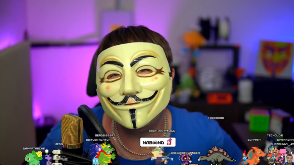 Streamer mit Maske vor Mikrofon und Gaming-Overlay als Symbol für Live Coding auf Twitch, Coding-Shows und Entwickler-Community